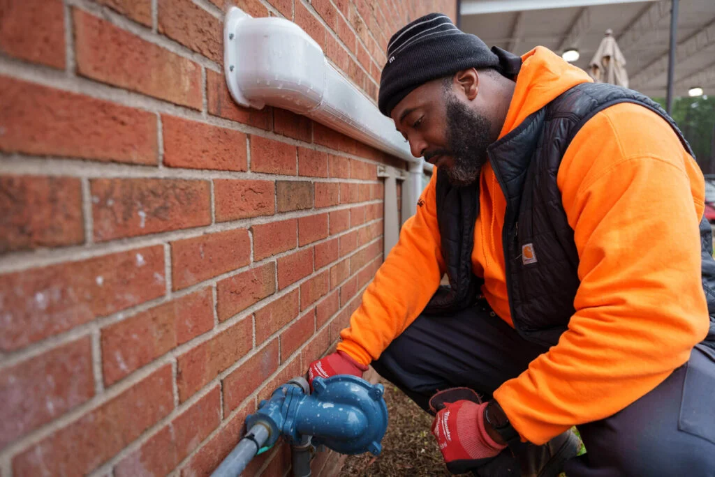 A CRG technician inspecting a commercial building wall for signs of a leak.